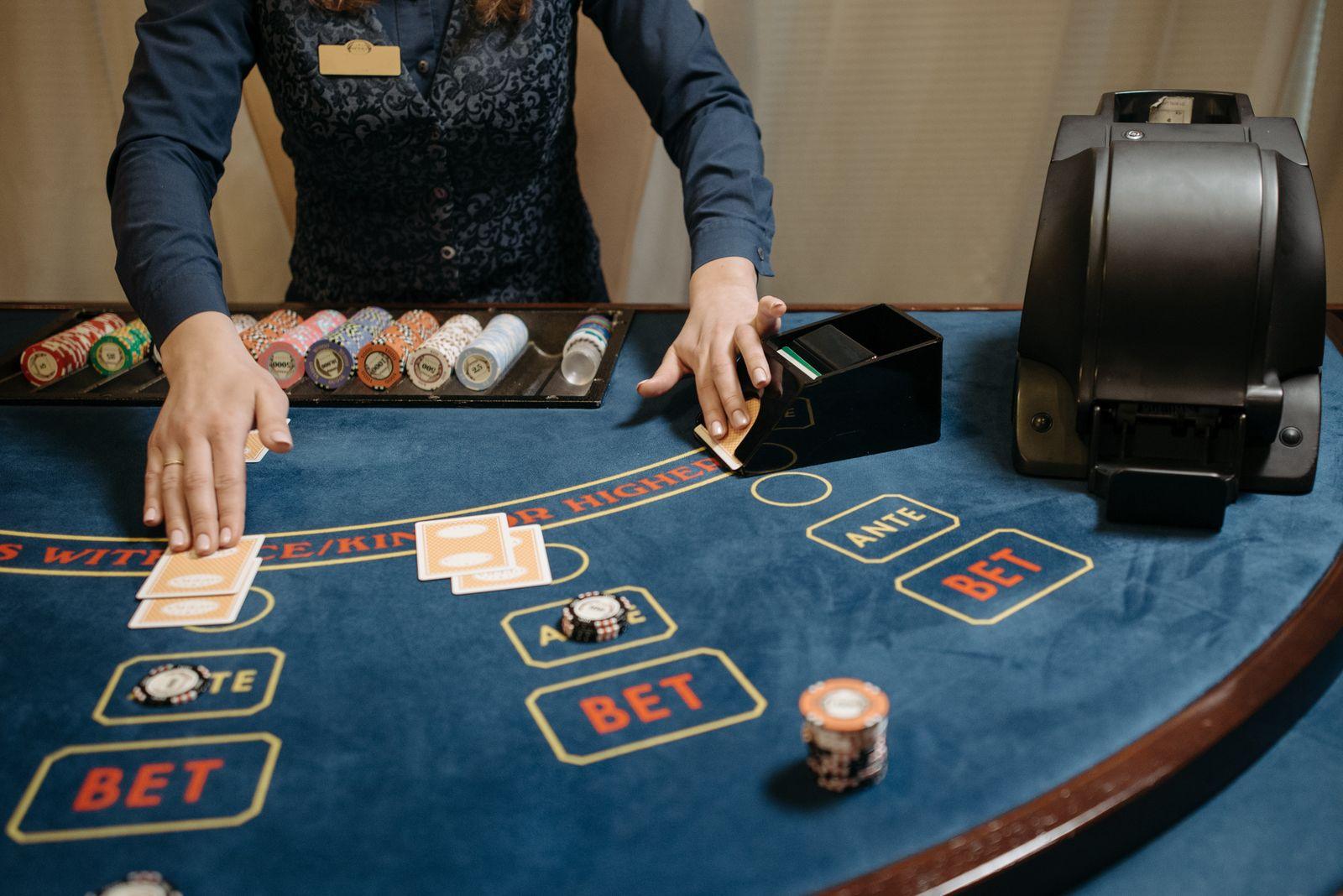 Live dealer dealing cards at a baccarat table with Player and Banker betting boxes